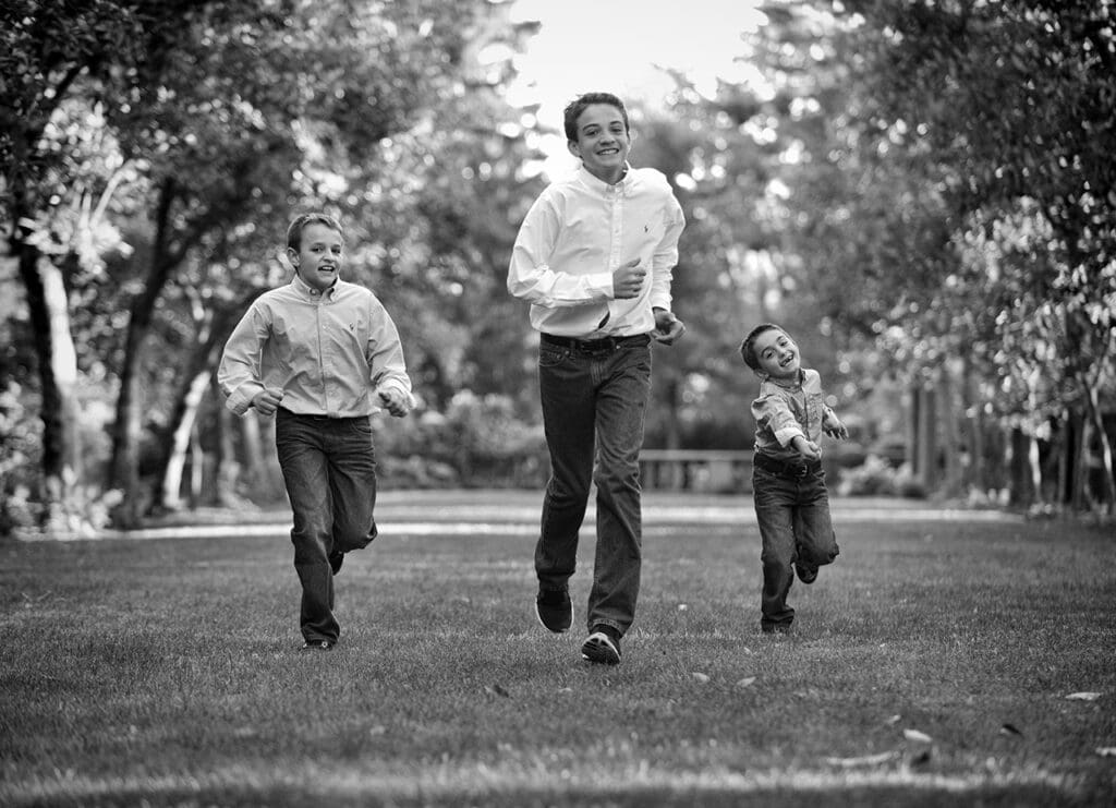 A man and two boys running in the grass.