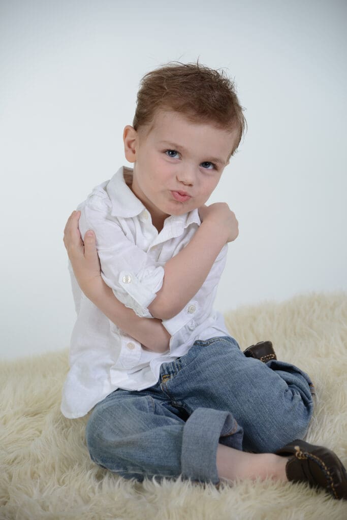 A young boy sitting on the floor with his arms crossed.