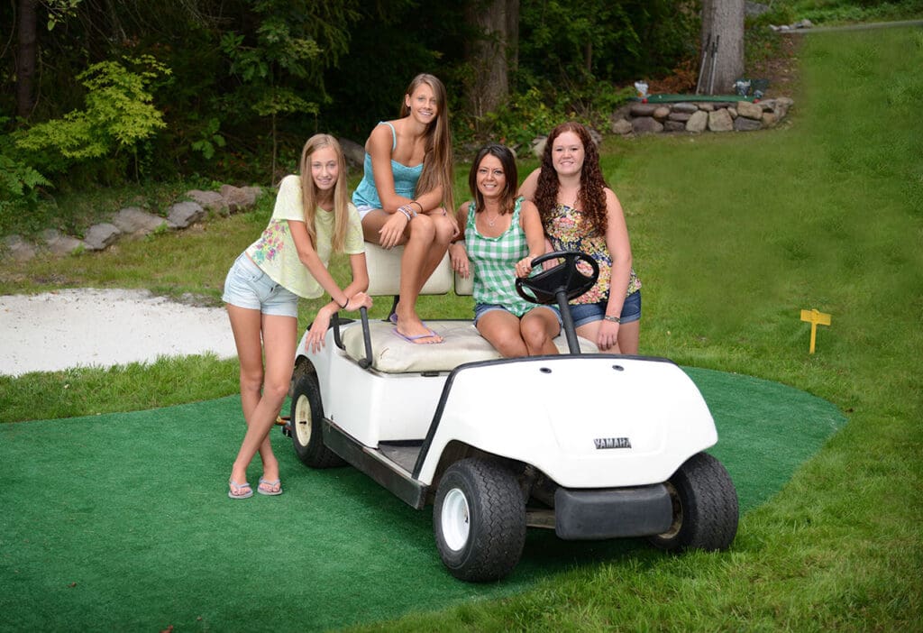 Four young women are posing on a golf cart.