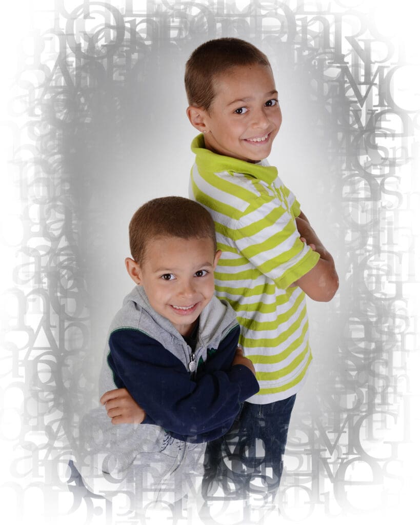 Two young boys posing for a picture in front of a mirror.