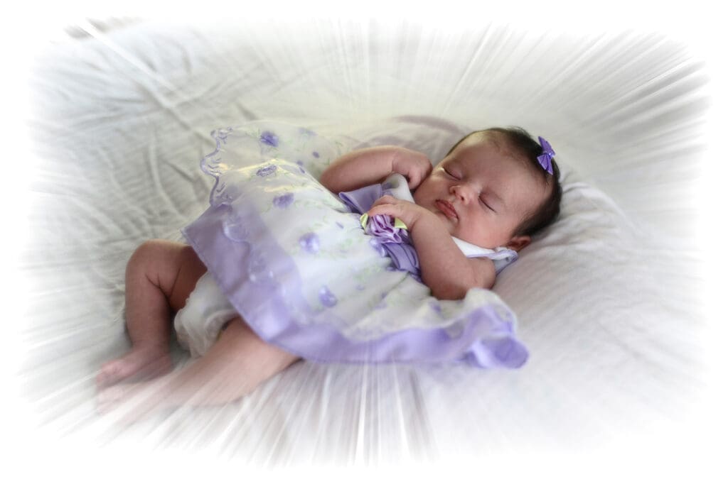 A baby girl is sleeping in her purple dress.