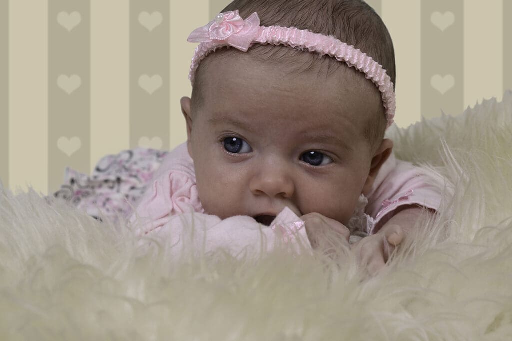 A baby girl with pink hair and bow in her head.