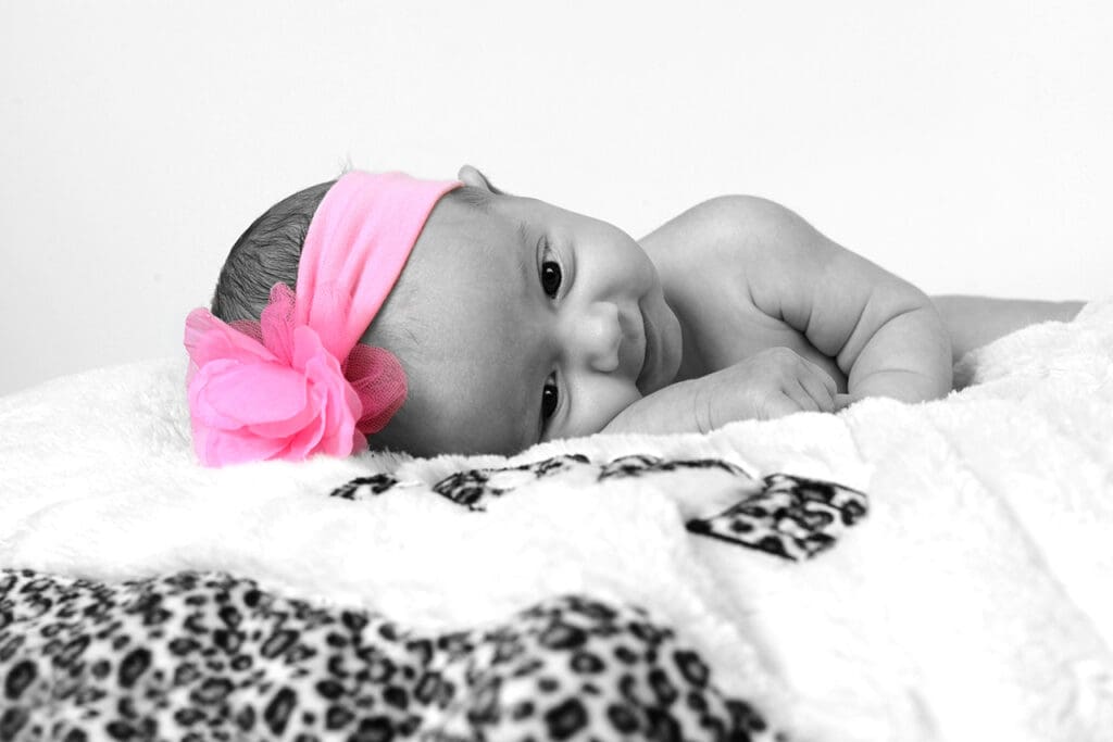 A baby girl with pink bow laying on top of her head.