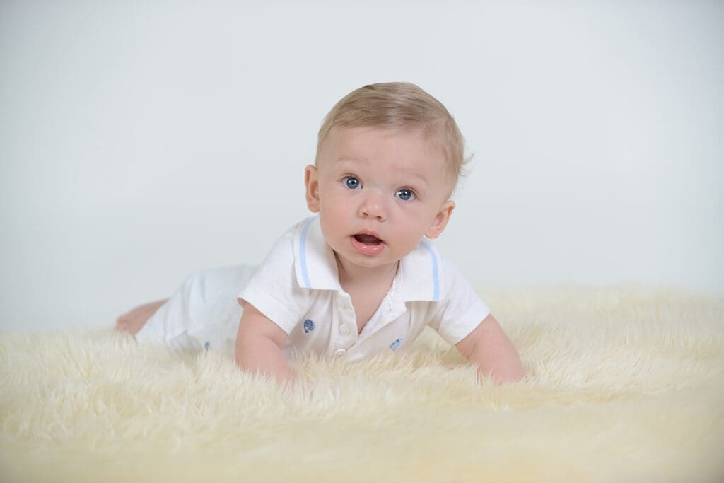 A baby laying on the ground looking at the camera.