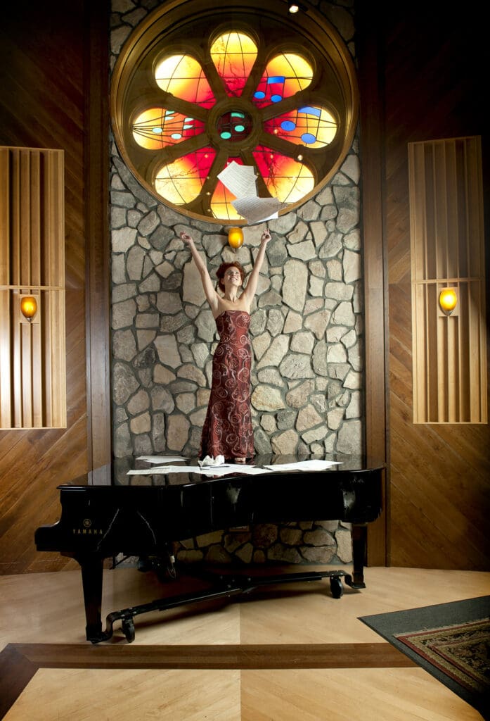 A woman standing in front of a piano.