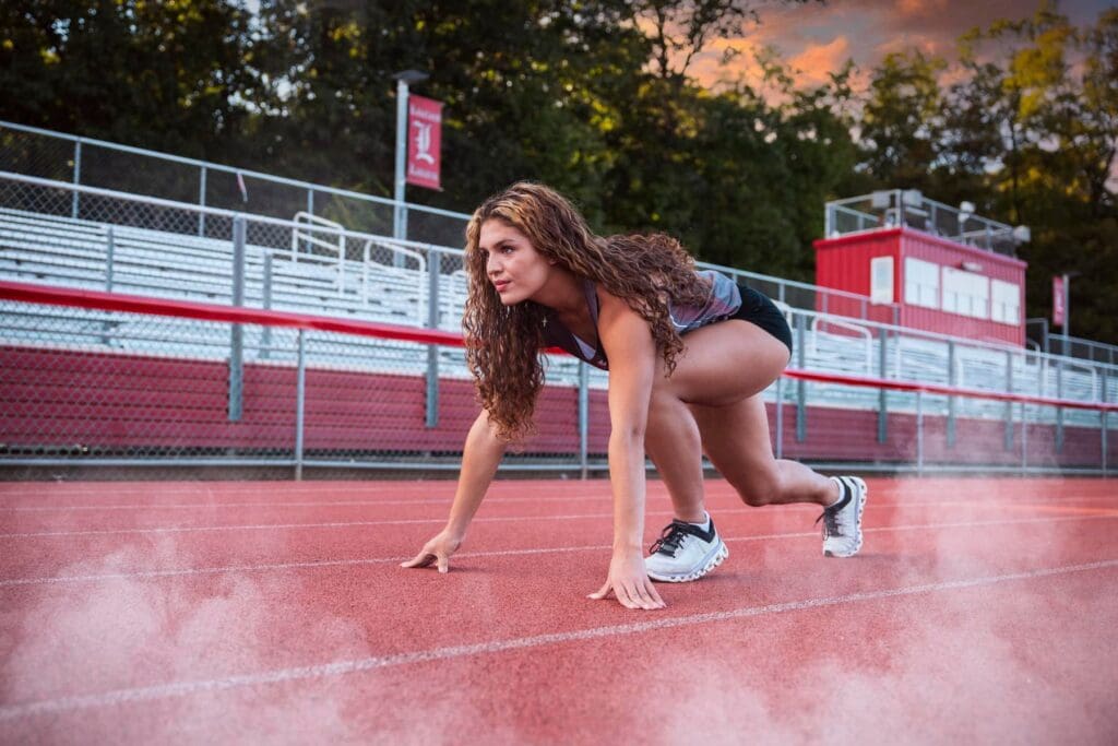 A woman is crouching on the ground in a race.