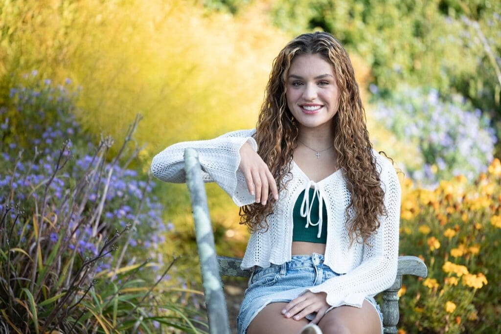 A girl sitting on top of a chair in the grass.