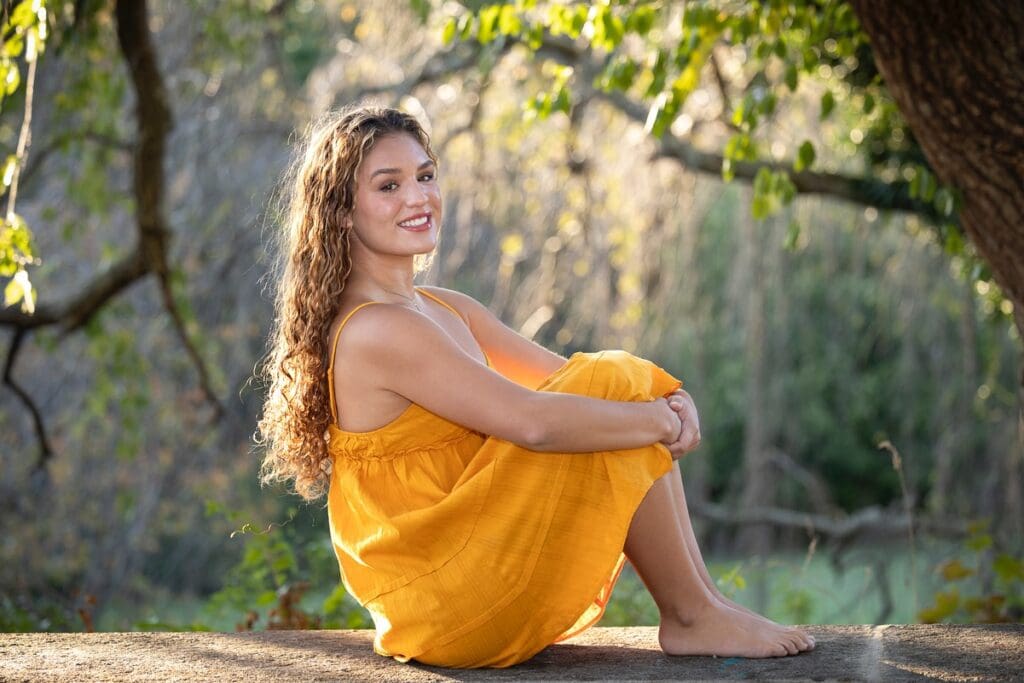 A woman in an orange dress sitting on the ground.