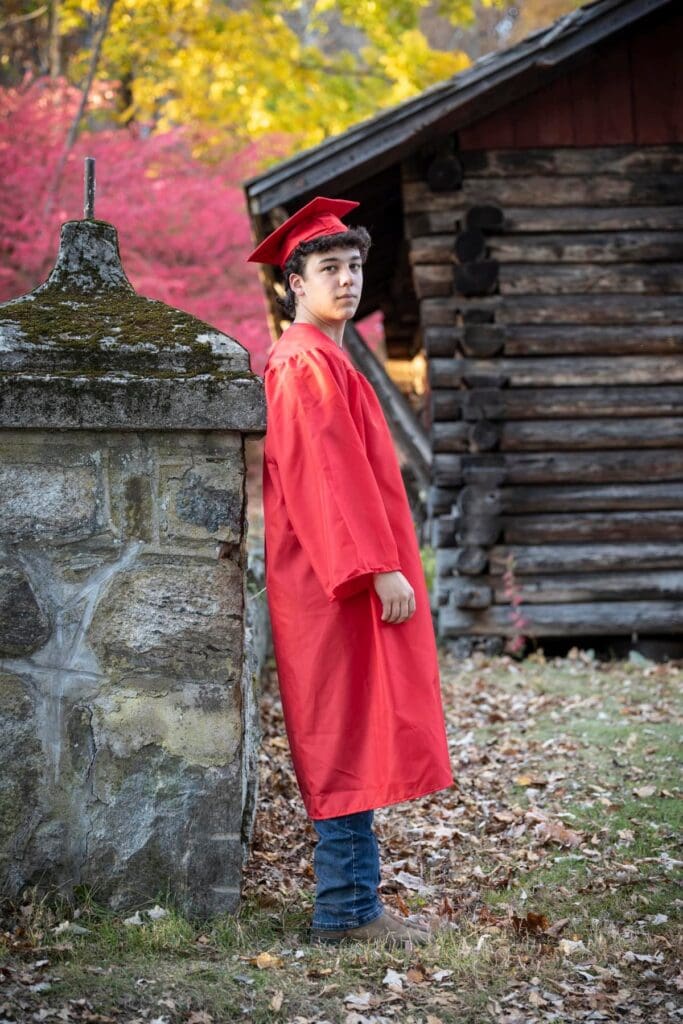 A young boy in red graduation cap and gown.