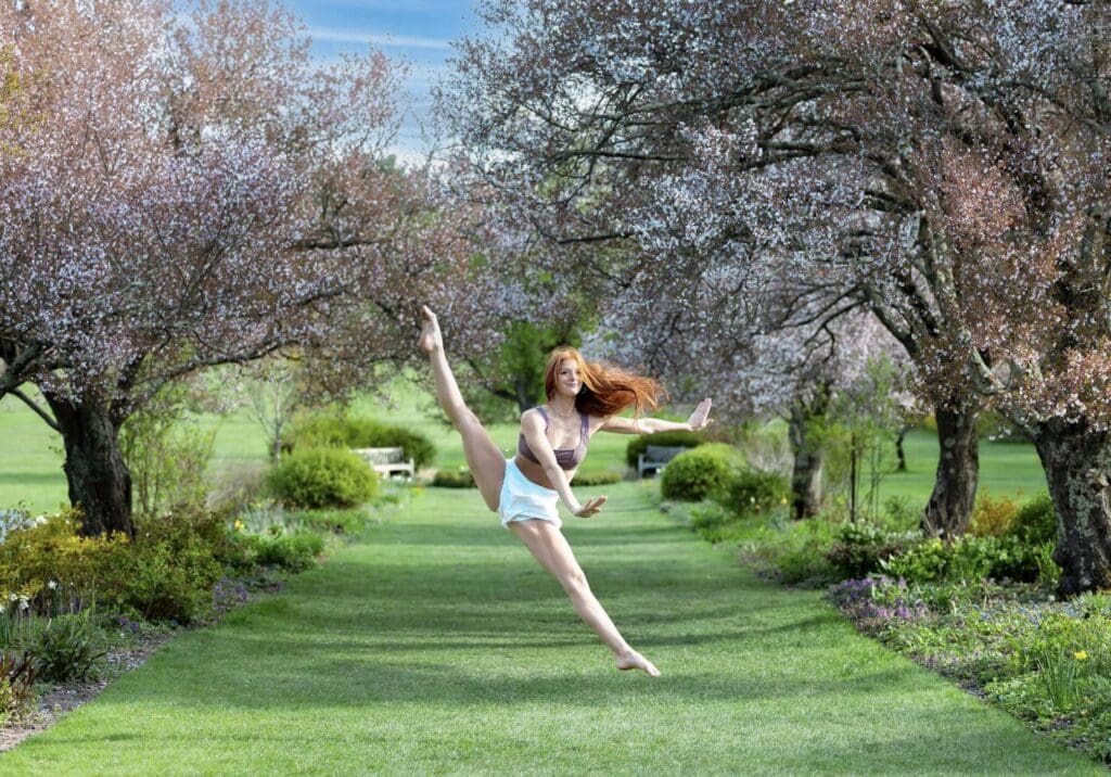 A woman in white shorts jumping on grass.