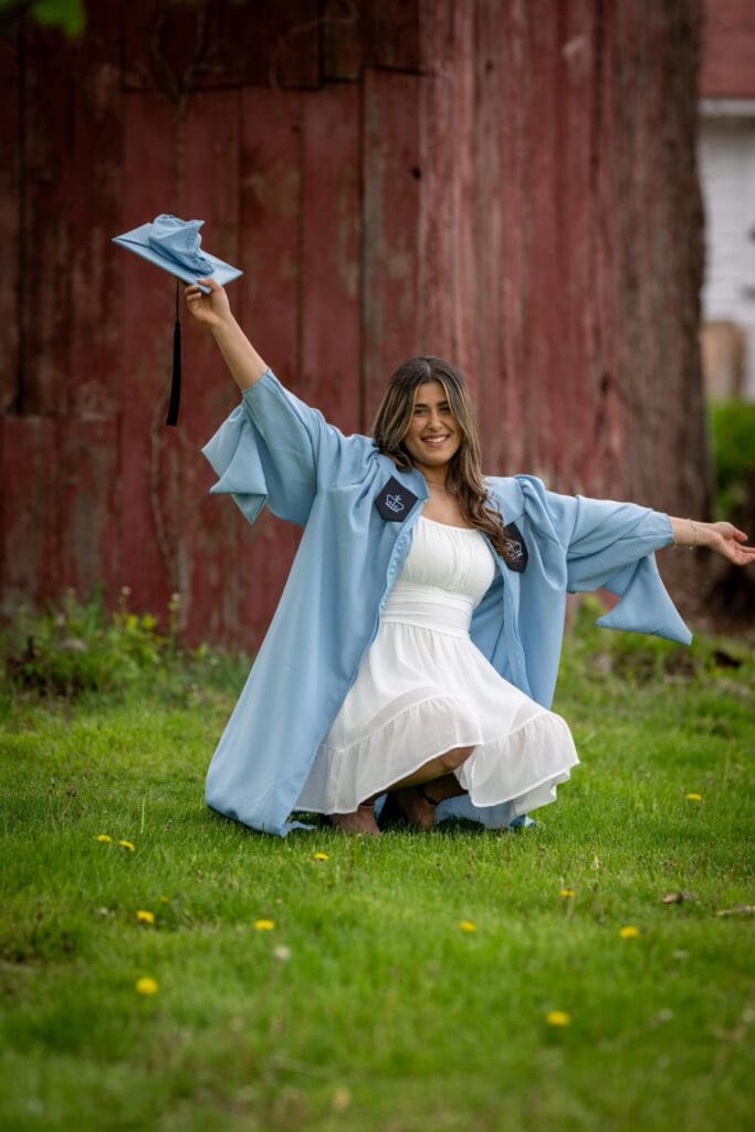 A woman in white dress and blue robe sitting on grass.